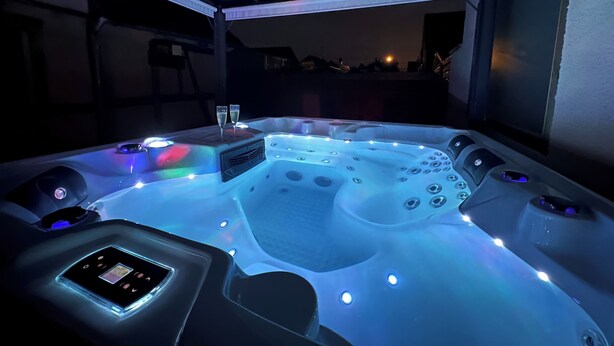 Un bain à remous doté de plusieurs jets, d’un panneau de commande et de deux coupes de champagne.