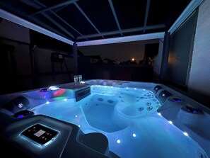 Un bain à remous doté de plusieurs jets, d’un panneau de commande et de deux coupes de champagne.