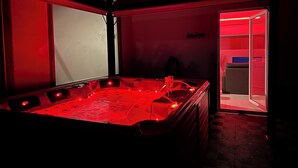 Une pièce avec une table de billard éclairée de lumières rouges, une coupe de champagne et un panneau indiquant : « Pool Travels ».