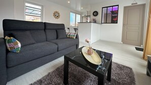 Un salon moderne avec un canapé gris, une table basse noire et un tapis moelleux.