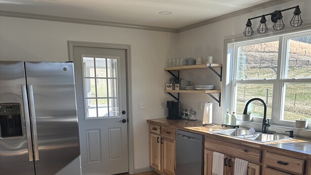 A kitchen with a stainless steel refrigerator, wooden cabinets, a dishwasher, and a window with a view of a yard. - Romantic cottage, pet friendly, stunning views of Smoky mtns. & Pigeon River.  (Clyde)