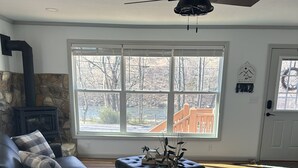 A living room with a stone fireplace, a black leather sofa, a round coffee table with a vase, and a wooden chair. - Romantic cottage, pet friendly, stunning views of Smoky mtns. & Pigeon River.  (Clyde)