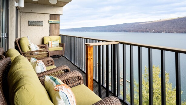 A balcony with wicker furniture, a ceiling fan, and a view of a lake.