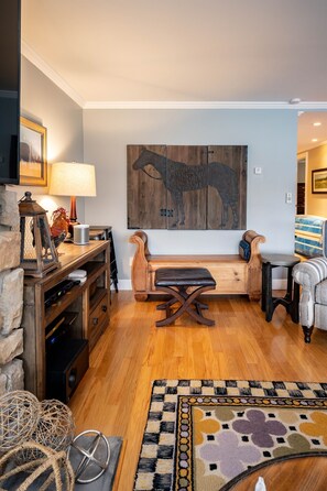 A living room with a wooden bench, a small table, and a rug.