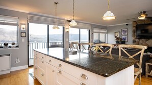 A kitchen with a large island, wooden flooring, and a view of the outdoors.