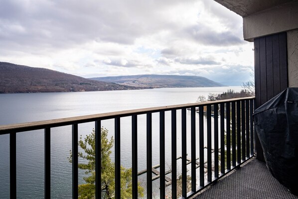 A balcony with a view of a lake and hills.