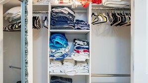 A well-organized closet with shelves for folded clothes, a hanging rod for garments, and a trash bin.
