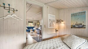 Ein Schlafzimmer mit Bett, Schminktisch und einem Flur, der in einen Wohnbereich mit Sofa und Tisch führt.