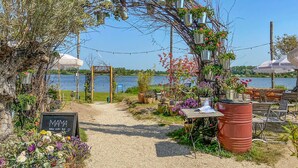 Ein Garten mit Kiesweg, der zu einem hölzernen Bogen führt, umgeben von Blumentöpfen und Sitzgelegenheiten im Freien.