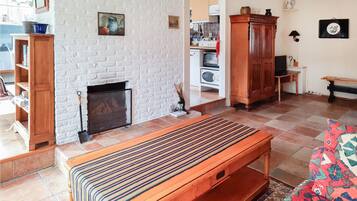 Een woonkamer met een open haard, houten meubels, een vloerkleed met patroon en een televisie.