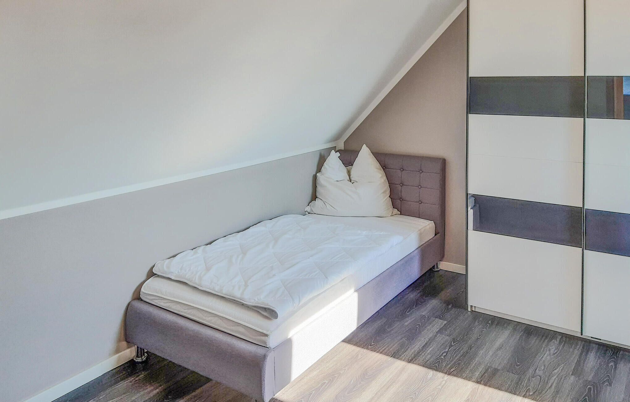 A small bedroom with a bed, a wardrobe, and a sloped ceiling.