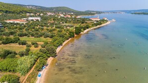 An aerial view of a coastal area with a beach, buildings, and a church. - Beach front home in Pasman (Pasman)