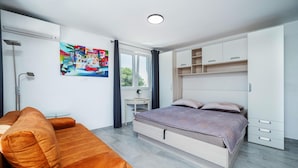 Un dormitorio moderno con cama, sofá, escritorio y un cuadro en la pared.