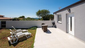 Un patio con mobiliario exterior, una parrilla y vistas al mar.