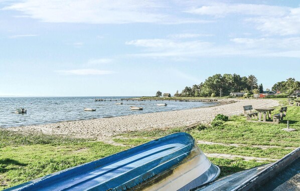 A beach with boats, a pier, and houses in the background.