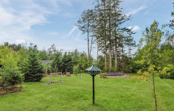 A grassy area with a gazebo, trees, and a distant building.