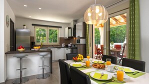 A modern kitchen with a dining area, featuring a breakfast setup with fruit, croissants, and orange juice. - Pet friendly home in Barban (Barban)