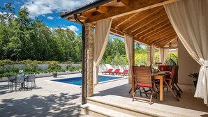 A covered outdoor area with a pool, red lounge chairs, and a table with chairs. - Pet friendly home in Barban (Barban)