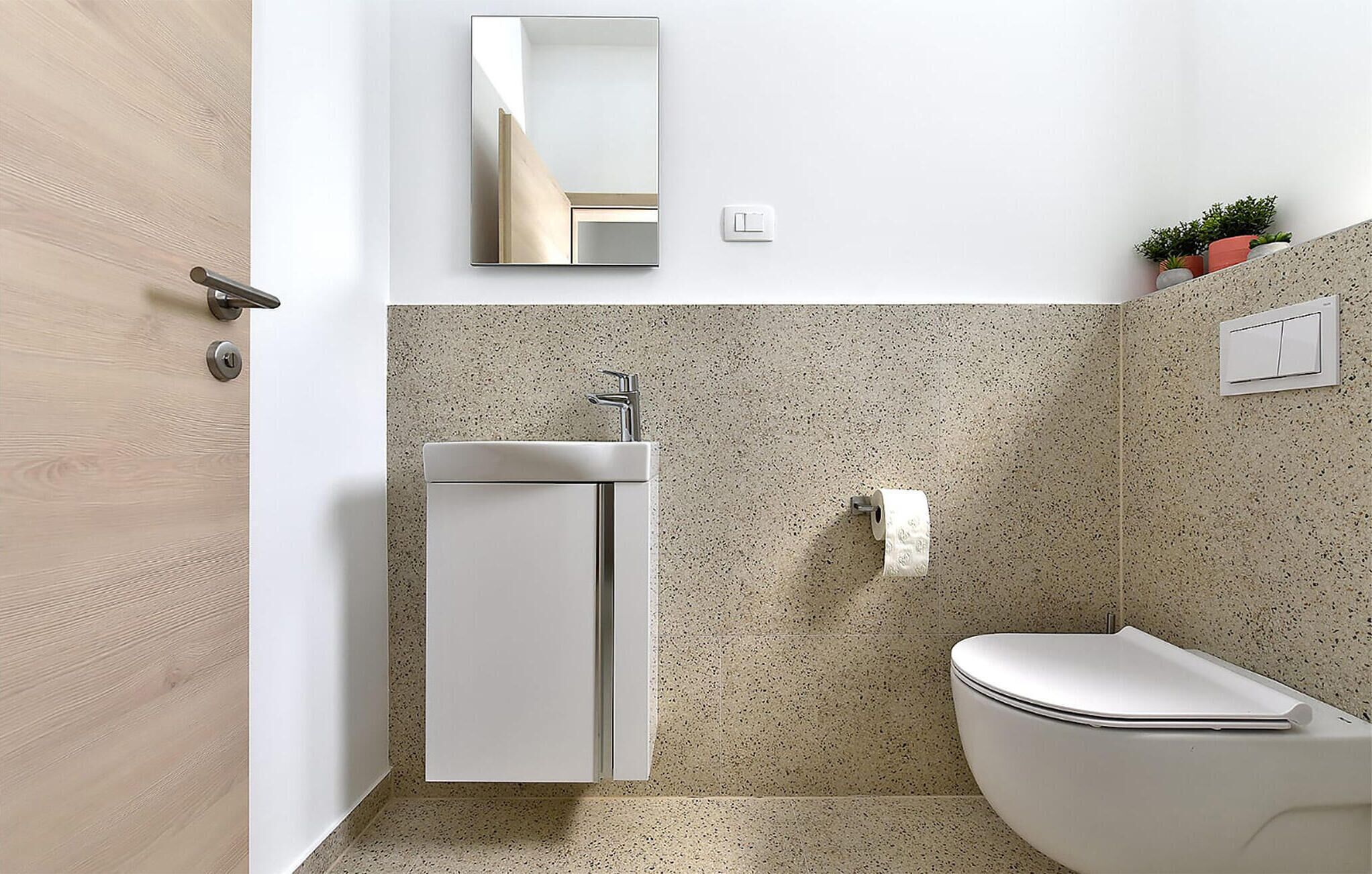 A bathroom with a toilet, sink, and mirror.