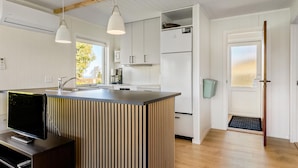 Cocina moderna con isla central, muebles blancos e iluminación colgante.