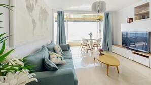 A modern living room with a sofa, TV, and dining area. - 1 bedroom lovely apartment in Cullera (Cullera)