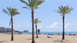 A beach with palm trees, a lifeguard tower, and a clear blue sky. - 1 bedroom lovely apartment in Cullera (Cullera)