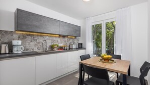 Une cuisine moderne avec un coin repas, comprenant une machine à café, un grille-pain et un panier à fruits sur le plan de travail.