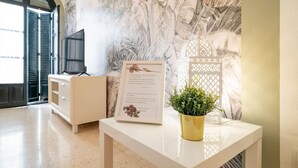 Een receptiegedeelte met een wit bureau, een ingelijst welkomstbericht, een potplant en een decoratieve witte wand.