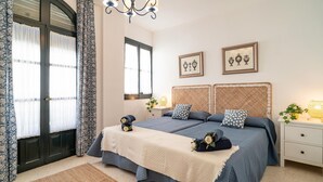 Een slaapkamer met een tweepersoonsbed, twee nachtkastjes, een kroonluchter en twee ingelijste foto's aan de muur.