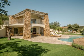 A stone villa with a balcony, a pool, and a well-maintained lawn. - VILLA MANDORLO 500 meters from the sea, with garden, private pool, and sea view (Castiadas)