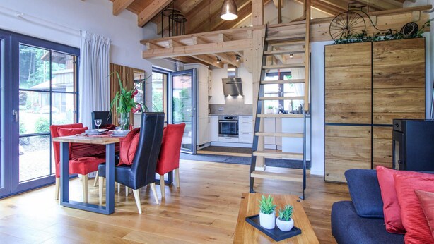 Amplia sala de estar con comedor, cocina y una escalera que conduce a un nivel superior.