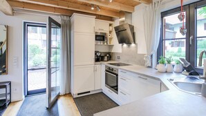 Una cocina moderna con gabinetes blancos, electrodomésticos de acero inoxidable y un ventanal grande.
