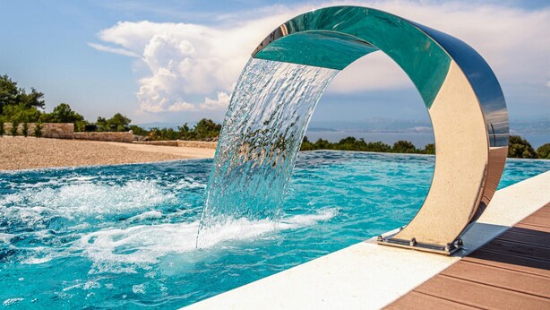 Una piscina con un elemento d'acqua curvo.