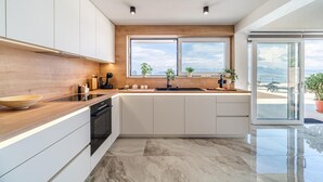 Una cucina moderna con mobili bianchi, un piano di lavoro in legno e un'ampia finestra con vista sull'esterno.