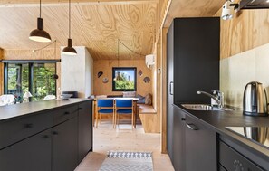 A modern kitchen with wooden cabinetry, a black countertop, and a stainless steel sink.