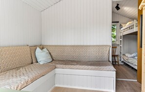 A room with a corner sofa, a bunk bed, and a small table.