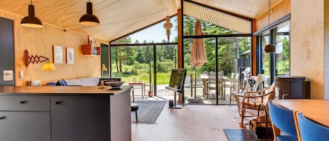 Een moderne keuken met een groot eiland, houten plafond en grote ramen met uitzicht op de omgeving.