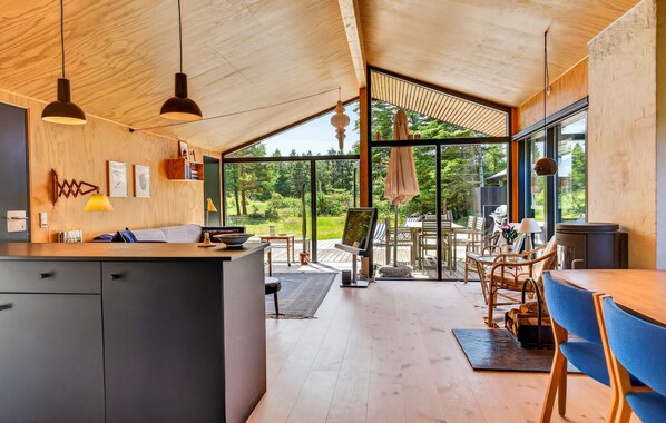 A modern kitchen with a large island, wooden ceiling, and large windows offering a view of the outdoors. - Awesome home in Saltum with WiFi (Saltum)