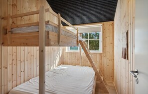 A wooden cabin room with a bunk bed, a window, and a door. - 3 bedroom amazing home in Jerup (Jerup)