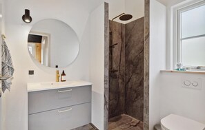 A modern bathroom with a marble shower enclosure, a round mirror, and a white toilet. - 3 bedroom amazing home in Jerup (Jerup)