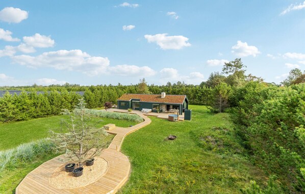 A modern house with a green roof, surrounded by a well-maintained garden and a wooden deck. - 3 bedroom amazing home in Jerup (Jerup)