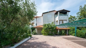 A two-story building with a tiled roof, a covered outdoor area with a green canopy, and a paved walkway.