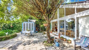 A garden patio with a blue shed, a tree, and a large glass house. - 4 bedroom pet friendly home in Quiberon (Quiberon)