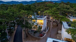 Une maison moderne dotée d’un balcon, entourée d’arbres et offrant une vue sur la montagne.