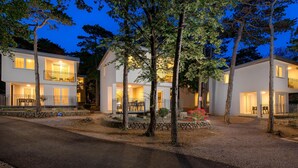 Un immeuble résidentiel de deux étages doté de balcons, d’un chemin pavé de pierres et d’un petit jardin agrémenté de fleurs rouges.
