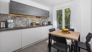 Une cuisine moderne avec des meubles blancs, un plan de travail gris, une machine à café, un four à micro-ondes et une table à manger avec des chaises.