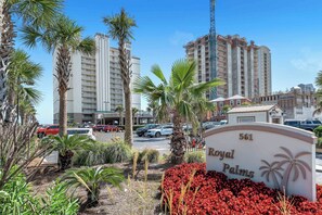 Une enseigne pour l’hôtel Royal Palms, avec des palmiers et des fleurs rouges au premier plan.