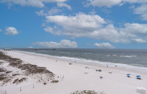 Enjoy a serene beach experience with a wide sandy shore and a picturesque pier extending into the calm ocean.