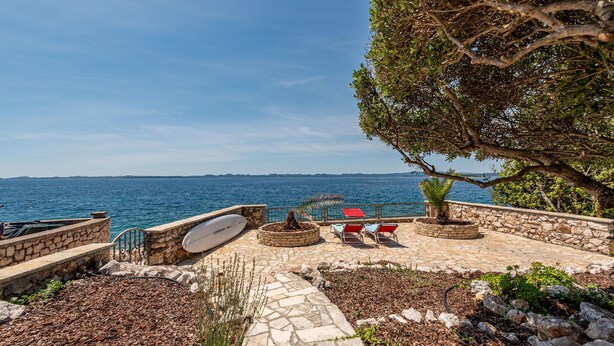A stone pathway leading to a seating area with a view of the sea.