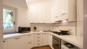A modern kitchen with white cabinets, a microwave, a sink, a stove, and a window with a view of greenery. - 3 bedroom amazing home in Parghelia -VV- (Parghelia -VV-)